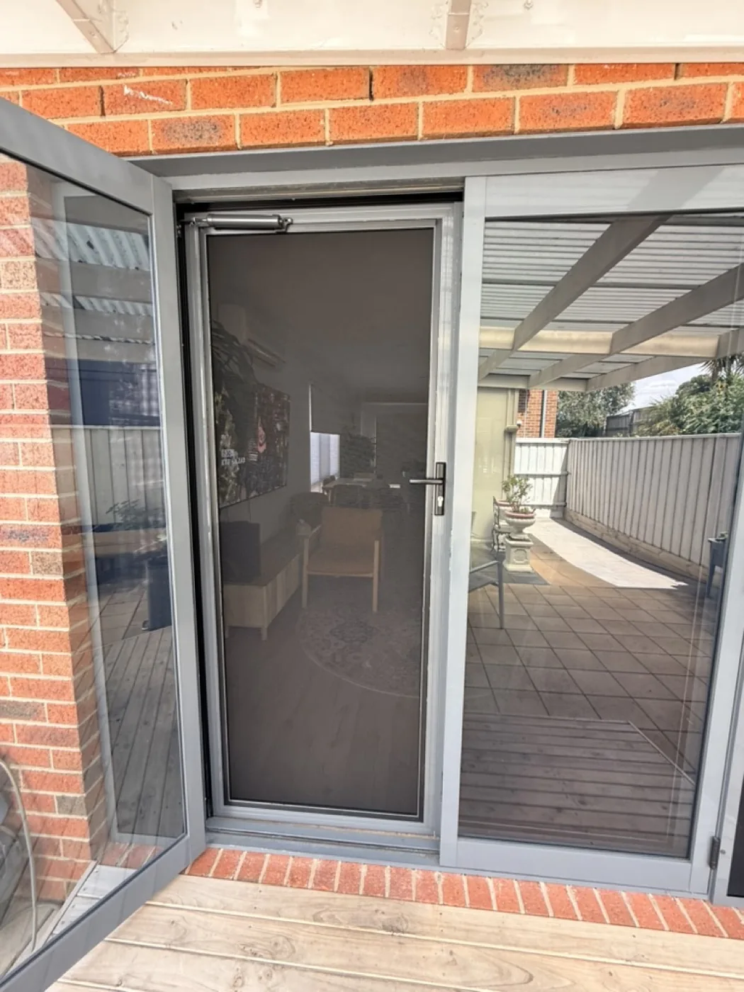 Grey security screen door on an enclosed porch with timber deck