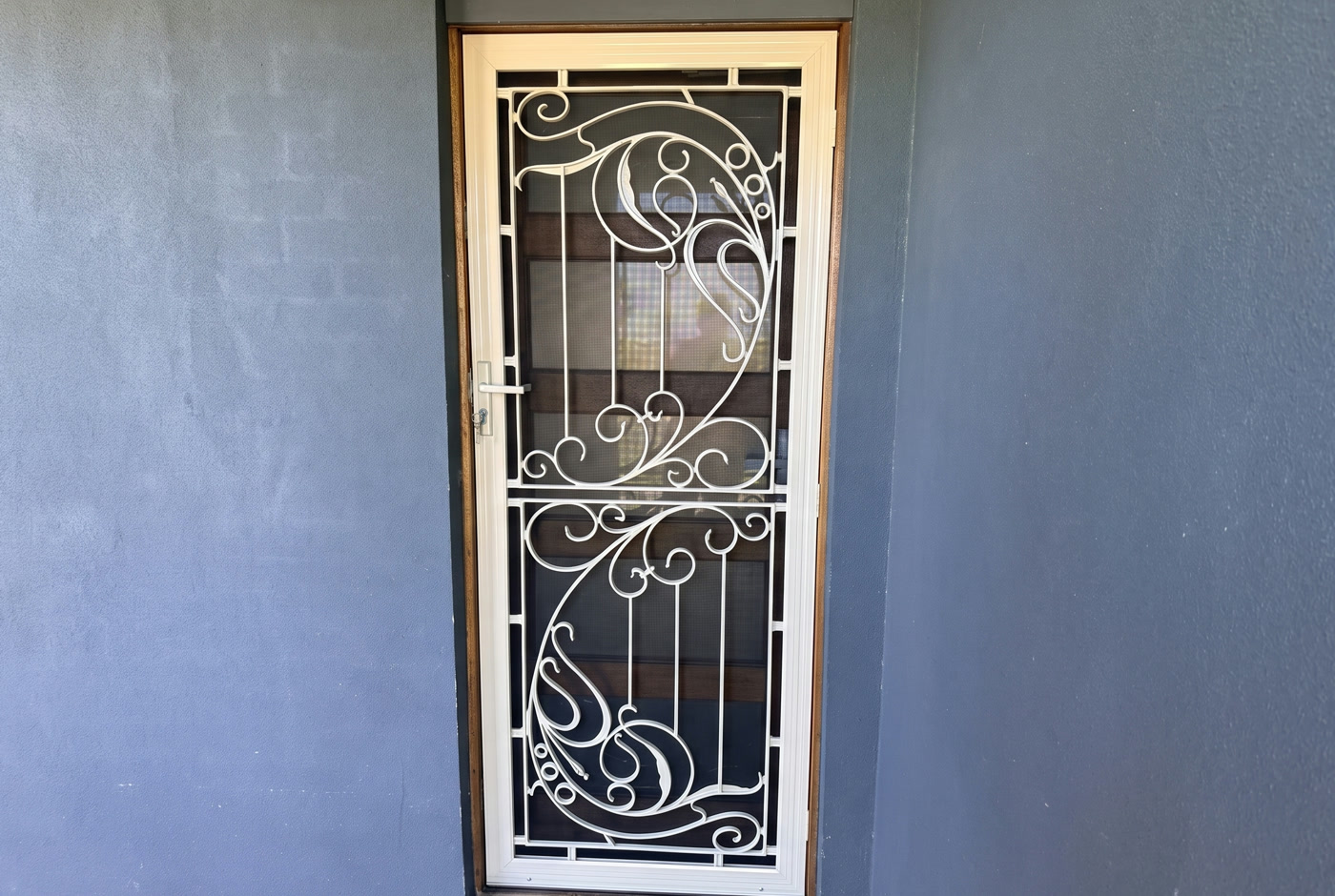 White wrought-iron scroll security door on a charcoal rendered Melbourne entrance