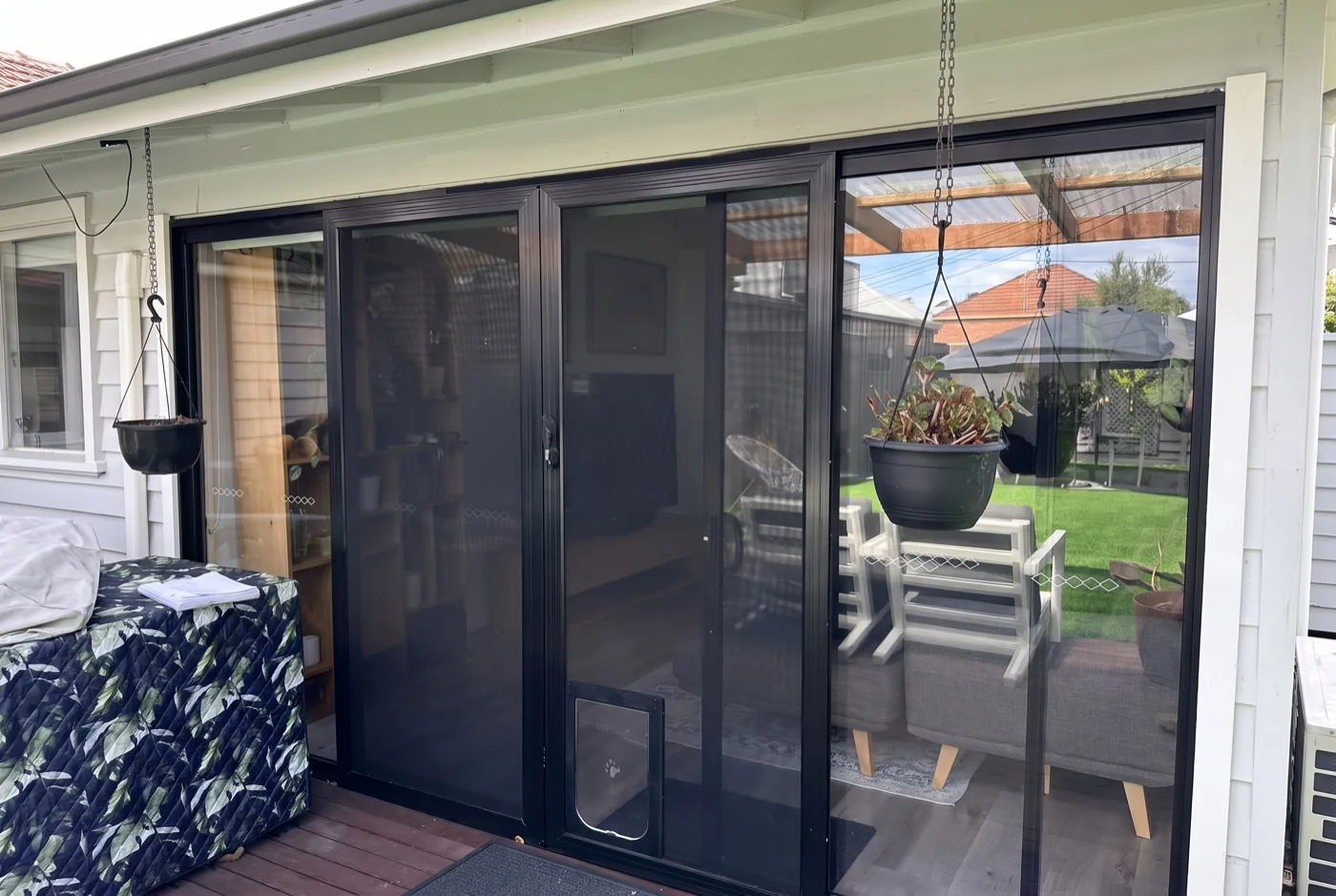 Black sliding security screen doors with built-in pet door on a Melbourne deck